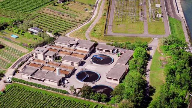 Sewage treatment facility with circular basins and industrial buildings, aerial view. Water purification infrastructure near Torbole, Italy