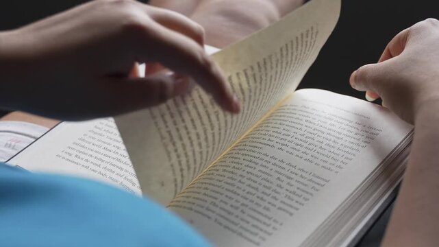 Close-up macro shot of a woman's fingers gently turning a page of an open book, with shallow depth of field, soft natural window light, and blurred background creating a dreamy intimate mood.