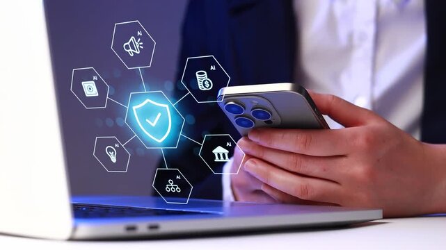 Person interacts with mobile phone while looking at laptop screen showing digital security icons related to technology and networks.