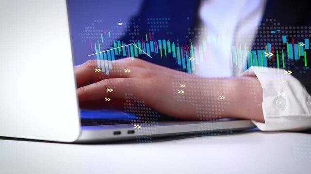 Hands typing on a laptop with financial graphs and data displayed on the screen in a modern work environment during daytime.