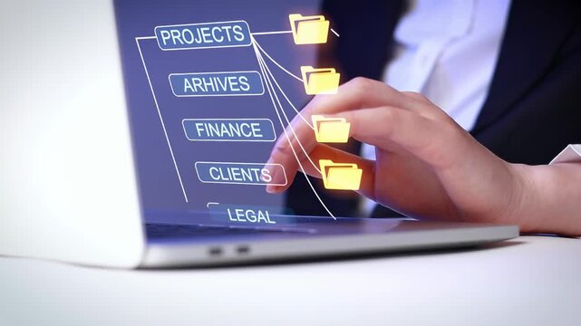 Working on a laptop with file management software during office hours to organize project and client folders.