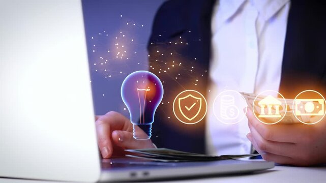 Business person uses a laptop while holding cash with a light bulb graphic showing an idea in a modern office setup.