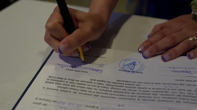 Close-up of hands signing marriage certificate with pen during wedding celebration