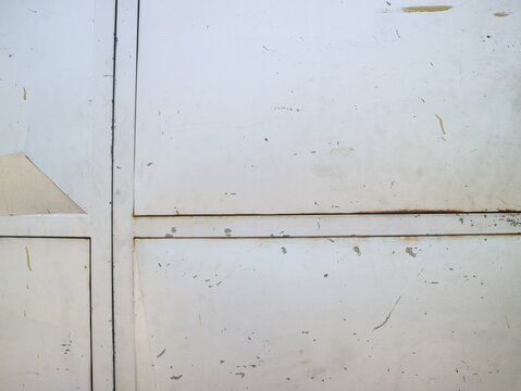 Close-up of a weathered white metal surface with scratches and rust spots