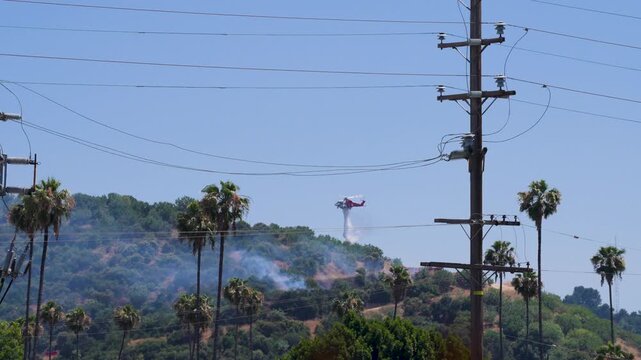 Slow motion shot of Los Angeles Fire Department responding to wildfire with aerial unit dropping water 