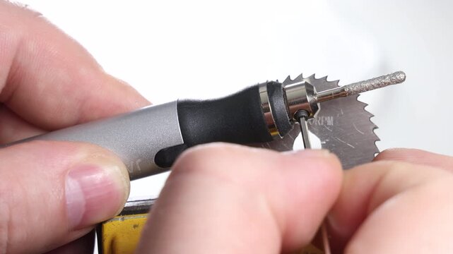 Close up of hands installing new diamond burr bit on precision rotary tool using allen key