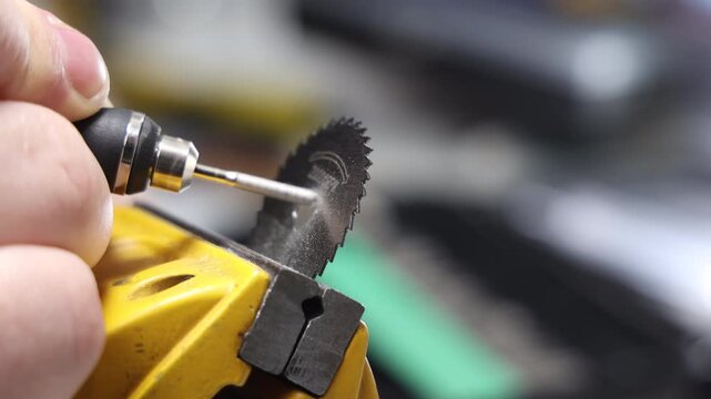 Close up of rotary tool grinding a circular saw blade in a vise with metal dust