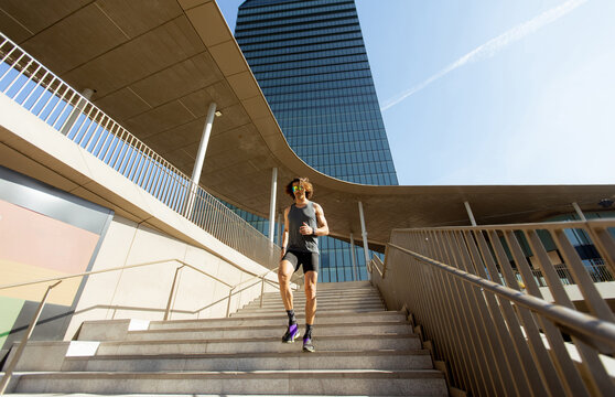Runner goes down stairs in city during bright day with tall building in background