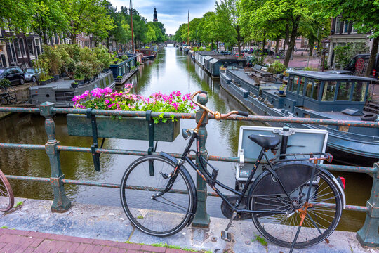 Altes Fahrrad lehnt an Gel&auml;nder &uuml;ber einer Gracht in Amsterdam