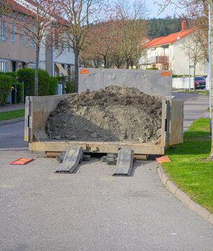 Construction debris container filled with soil placed on residential street.