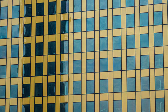 Modern office building facade with blue glass and beige panels.