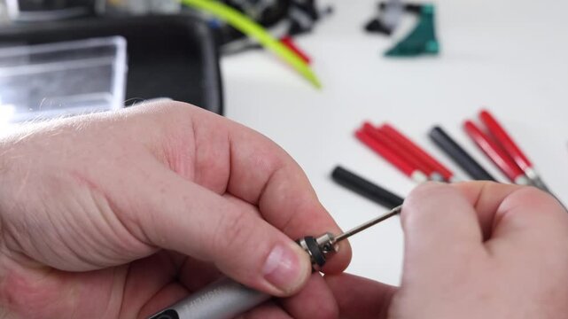 Technician preparing mini electric engraving pen and choosing attachments from a tool kit