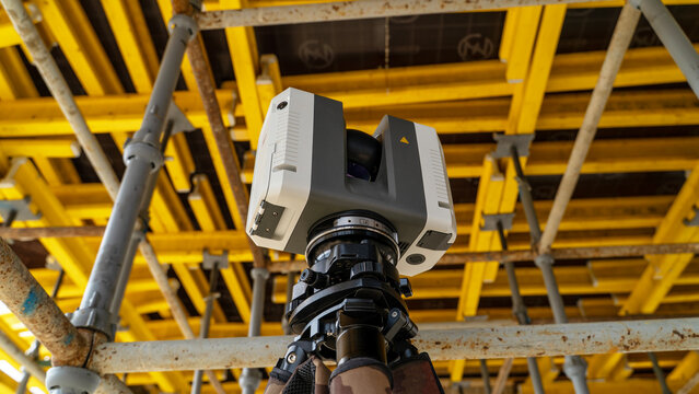 Construction site with scaffolding and 3D scanner mounted on tripod