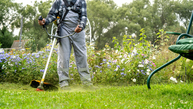 Man trims grass with a powerful weed wacker