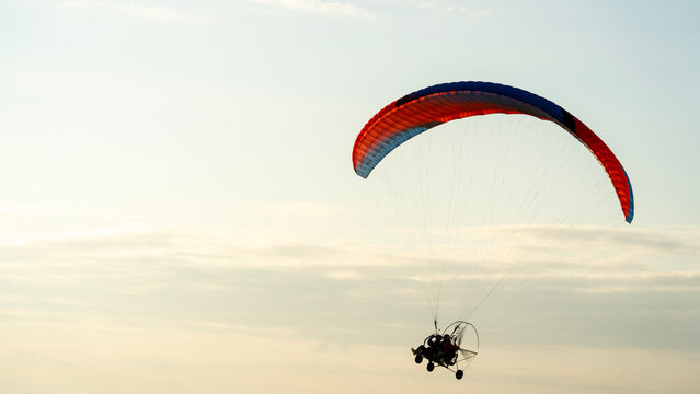 Paraglider soars against soft, hazy sky