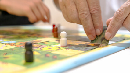 Obraz premium Hands move pieces on a colorful board game