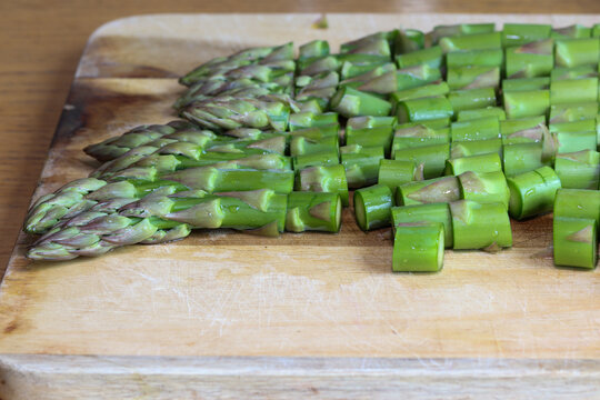 Chopped green asparagus on a kitchen board, preparing an asparagus dish.