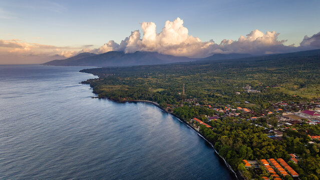 Aerial view of Tulamben coastline with dark beach and mountains, Bali, Indonesia at dusk
