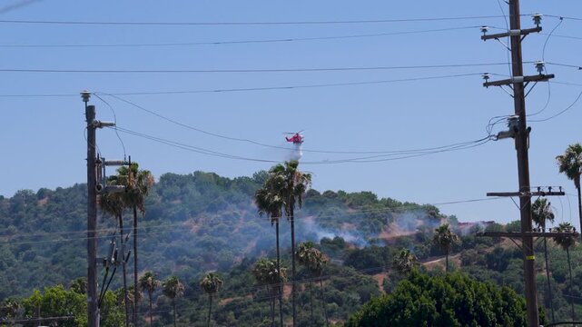 Slow motion shot of Los Angeles Fire Department responding to wildfire with aerial unit dropping water 