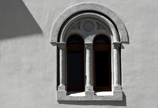 double arched windows with decorative stucco trim. old classic style. gray textured wall finish. ornate decorative elements. glass window. small half columns. old architecture concept