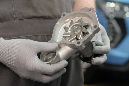 Car service center.Auto parts.Replacing the water pump. An auto mechanic holds a water pump in his hands. Inspection of a new water pump.
