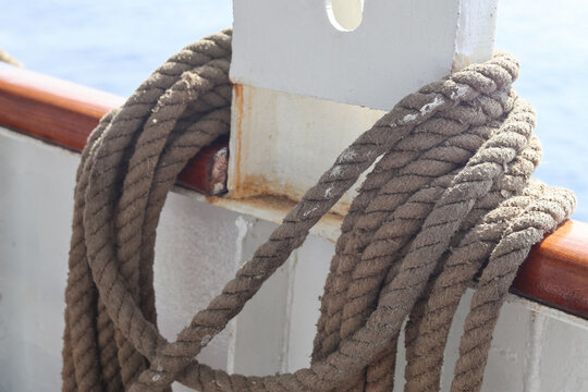 coiled nautical rope wrapped around a ship railing and deck structure, highlighting natural fiber texture, maritime equipment and marine transportation concepts with shallow depth of field and natural