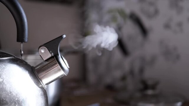 Close up, whistling metal boiling old kettle on stove in kitchen. Retro kettle with rising steam in rays of sunlight. Steam texture on a blurred background. Vintage. Cozy atmosphere. Morning