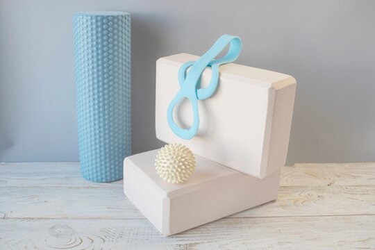 Equipment for yoga and pilates. Yoga blocks, roller, expander and massage ball on a wooden surface.