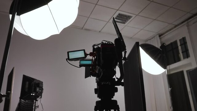 Backstage professional video camera and softbox lighting setup in a production studio. Concept filmmaking, media production, broadcasting, content creation, advertising, cinema and video technology.