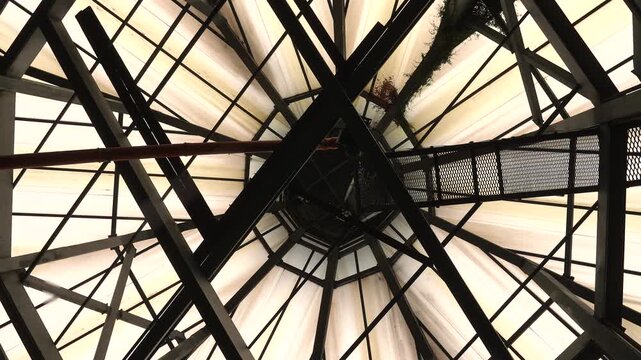 An upward perspective of a geometric steel and glass structure with intersecting lines. The concept highlights architecture, symmetry, and industrial design, perfect for construction themes.