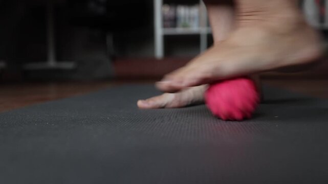 a woman gives herself a foot massage with a massage ball. tired legs. flat feet