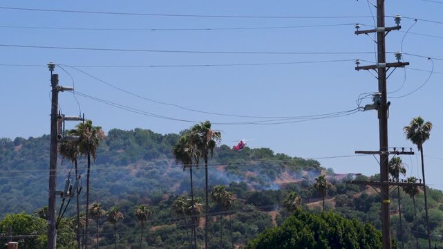 Slow motion shot of Los Angeles Fire Department responding to wildfire with aerial unit dropping water 