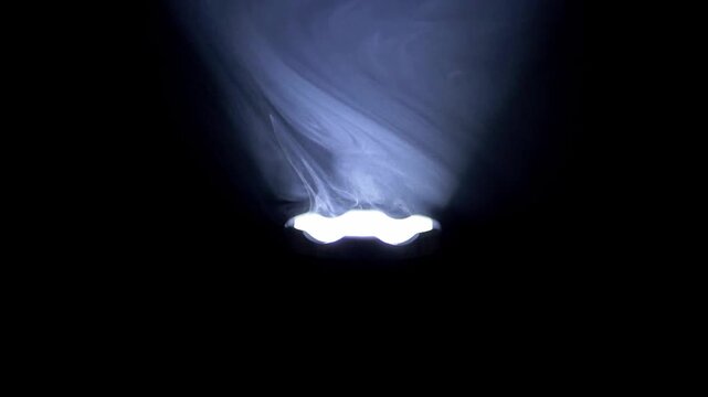 A vertical red flashlight beam cuts through swirling white smoke against a pitch black background in high contrast. Concept of mystery, emergency signaling, and paranormal investigation.