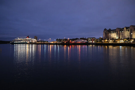 long-shot night view of Oslo Fjord harbor, city lights reflection of Oslo Havnelager and a cruise ship on the calm water surface