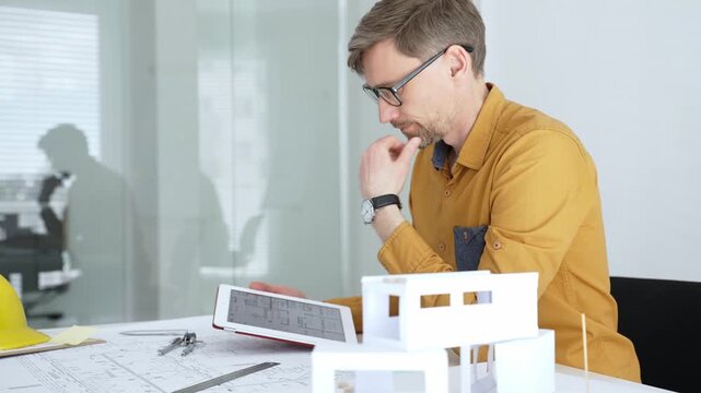 Architect working on architectural blueprint and scale model, designing and planning a new building project, focusing on engineering details and construction plans in a modern office