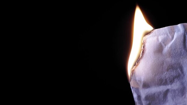 Blank white paper ignites and burns with a bright orange flame against a dark background, depicted from a side view. This visual represents the destruction of evidence, censorship, danger,