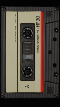 Vintage Audio Cassette Reels Spinning. Retro compact cassette tape with spinning reels on black background.	