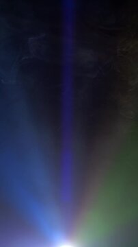 Projector light ray piercing atmospheric smoke, building dramatic volumetric glow against dark background.