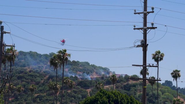 Slow motion shot of Los Angeles Fire Department responding to wildfire with aerial unit dropping water 