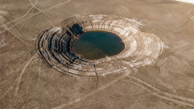 Aerial top view of shrinking reservoir lake with exposed sediment rings in arid desert landscape, severe water scarcity drought crisis concept, editorial environmental with copy space