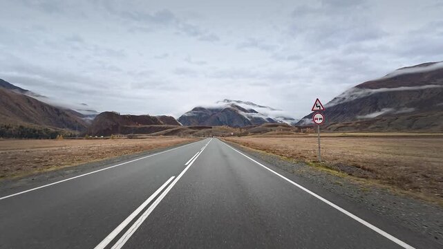 Empty Chuysky Trakt road through misty Altai mountains in late autumn under cloudy sky during cinematic road trip