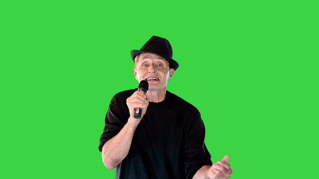 A senior man sings a song into the mic walking in a funny manner on a Green Screen, Chroma Key.
