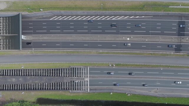 Top down aerial drone footage of traffic moving through the Coentunnel on the A10 ring road in Amsterdam. Major transportation infrastructure in the Netherlands viewed from above.