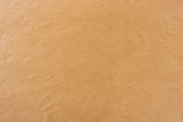 Fototapeta premium Close-up view of a textured brown paper background with subtle creases