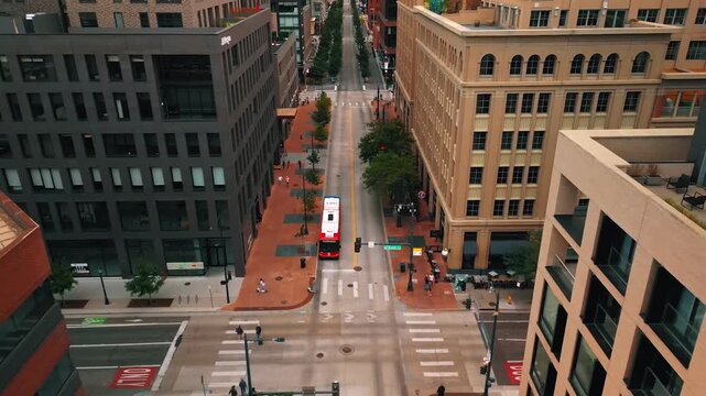 Aerial drone shot of downtown Denver city street with bus at intersection and tall buildings.
