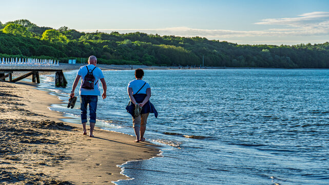 Senior couple walking along sandy beach on a sunny day by the Baltic Sea