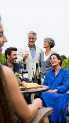 Obraz premium Adult daughter and her partner sharing a hilarious anecdote with her parents during a casual wine country reunion.