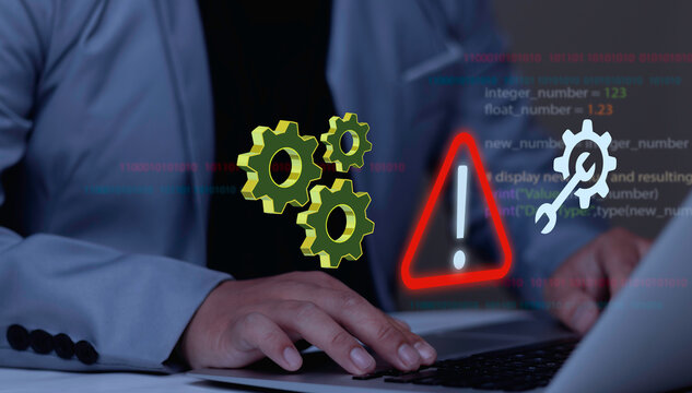 Programmer using laptop with triangle caution warning sign hologram. IT staff developer managing notification error, software update, and system maintenance.