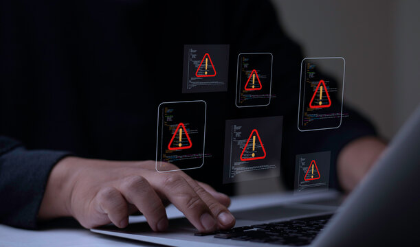 Programmer using laptop with multiple coding windows showing triangle caution warning signs. IT developer experiencing system software error and cyber security threat.