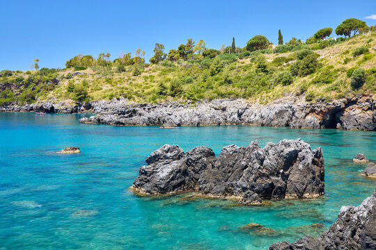 Scenic rocky bay with crystal clear turquoise water and green hills in Scalea, Calabria, Italy. Beautiful Mediterranean coastal landscape on a sunny summer day.